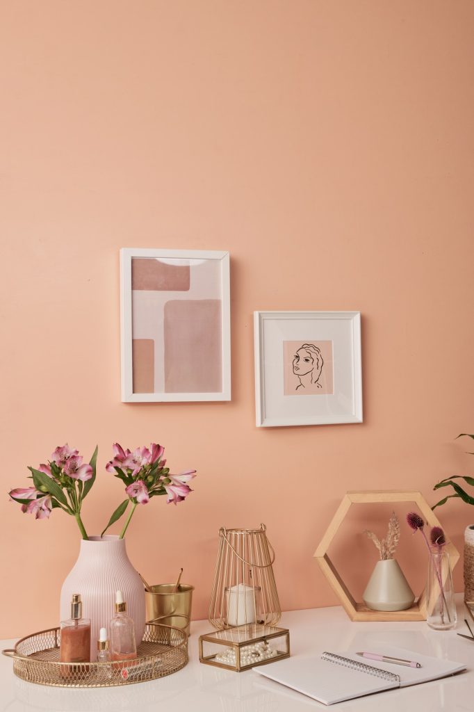 Workplace of interior designer by pink wall with two pictures in frames by table
